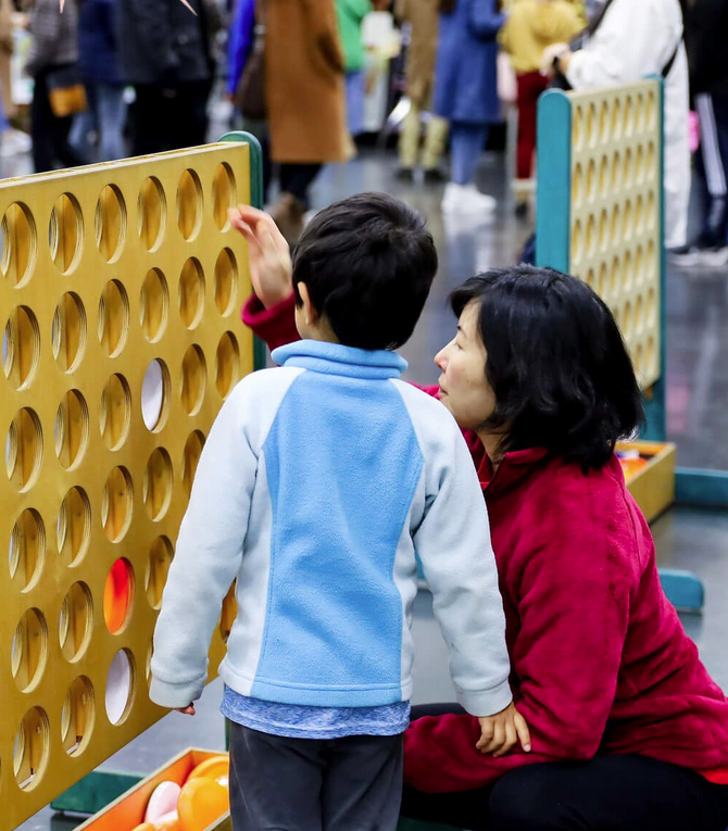 An image of an adult and child looking at a large-scale Connect Four game.
